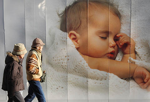 Japan, like many others countries, is getting creative when it comes to combating its population decline. Shown here, an older Japanese couple walks past an advertisement displaying a picture of a baby.